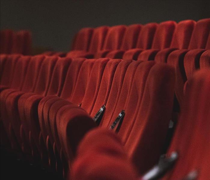 Photo of empty red velvet seats in a theatre.